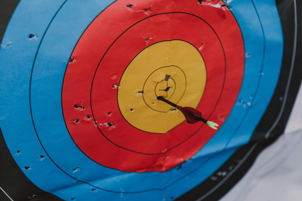Close-up of a target in archery with a single arrow hitting the bullseye, showcasing precision and skill.